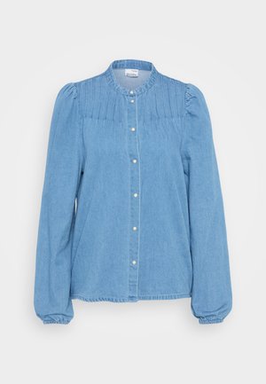Hele sinine denimsärk nööbiga, pika varrukaga, kogutud õlavarre detailidega ning vertikaalsete voldidega kaelakaeluses. Üksluisest kangast tekstuur.