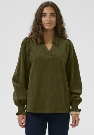 Grüne Cordbluse mit V-Ausschnitt, Puffärmeln und gerafften Manschetten. Der Stoff hat eine weiche Textur und eine lockere Passform.