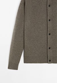 Grå ullcardigan med en texturerad yta, knappstängning och ribbade ärm- och nederkant. Tyget har ett mjukt, varmt utseende.