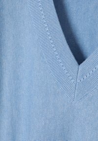 Pulover tricotat de culoare albastru deschis, cu un design în formă de V, textură ribbed vizibilă și cusături proeminente de-a lungul gâtului.