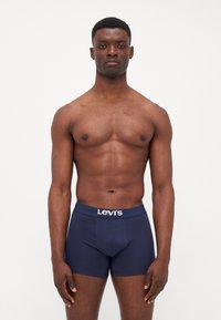 Marinblå boxershorts i mjukt tyg; har en logoband med "Levi's" i vitt. Designen är åtsittande med en slät yta.