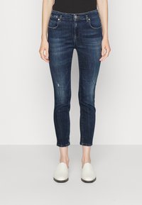 Mörkblå denimjeans med smal passform, urblekta accenter, slitna detaljer på benen och femficksdesign, ihop med vita slip-on skor.