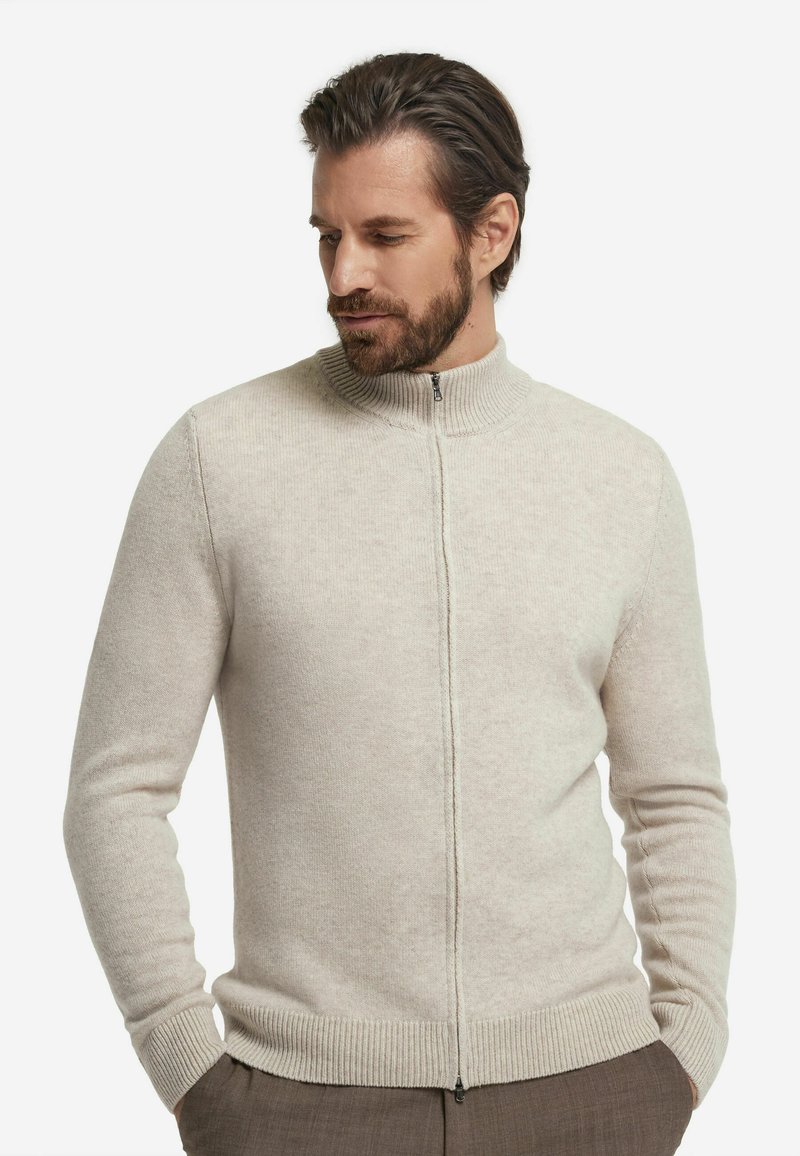 Hellbeiger Zip-up-Pullover aus weichem Strickmaterial, mit hohem Kragen, gerippten Bündchen und Saum, in schlanker Passform.