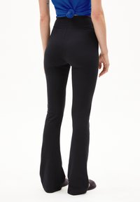 Zwarte flared leggings met een hoge tailleband, gemaakt van een zachte stretchstof, met een gladde textuur en minimale naden.