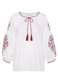 Witte blouse met rode geborduurde bloemmotieven op de mouwen, met een keyhole-halslijn en rode franjes, en geplooide pofmouwen.