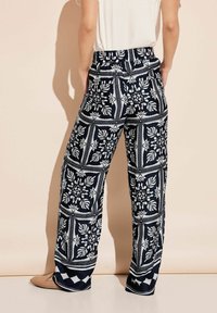 Marineblauwe wijd uitlopende broek met een witte bloemenmotief, elastische tailleband en zachte stof. Comfortabele pasvorm met een ontspannen vorm.