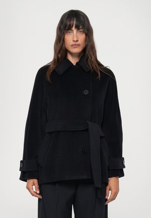Black wool coat with a collar, double-breasted buttons, a belt at the waist, and wide sleeves. Features side pockets and textured fabric.