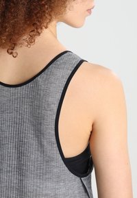 Grijs geribbeld tanktopje met zwarte biezen, voorzien van een racerback ontwerp. Het materiaal lijkt zacht te zijn met een lichte textuur.