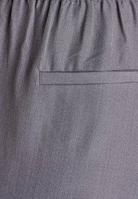 Sivá sukňa s elastickým pásom, hladkou textúrou, plochou zadnou vreckou a jemným melírovaným vzorom. Minimalistický a praktický dizajn.