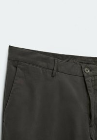 Pantalon gris foncé avec fermeture à bouton et fermeture éclair, doté de poches latérales et de passants pour ceinture, posé à plat sur une surface blanche.
