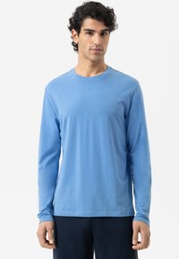 Lange mouwen blauwe shirt gemaakt van zachte stof, met een ronde halslijn en aangesloten mouwen, gecombineerd met donkere broeken.