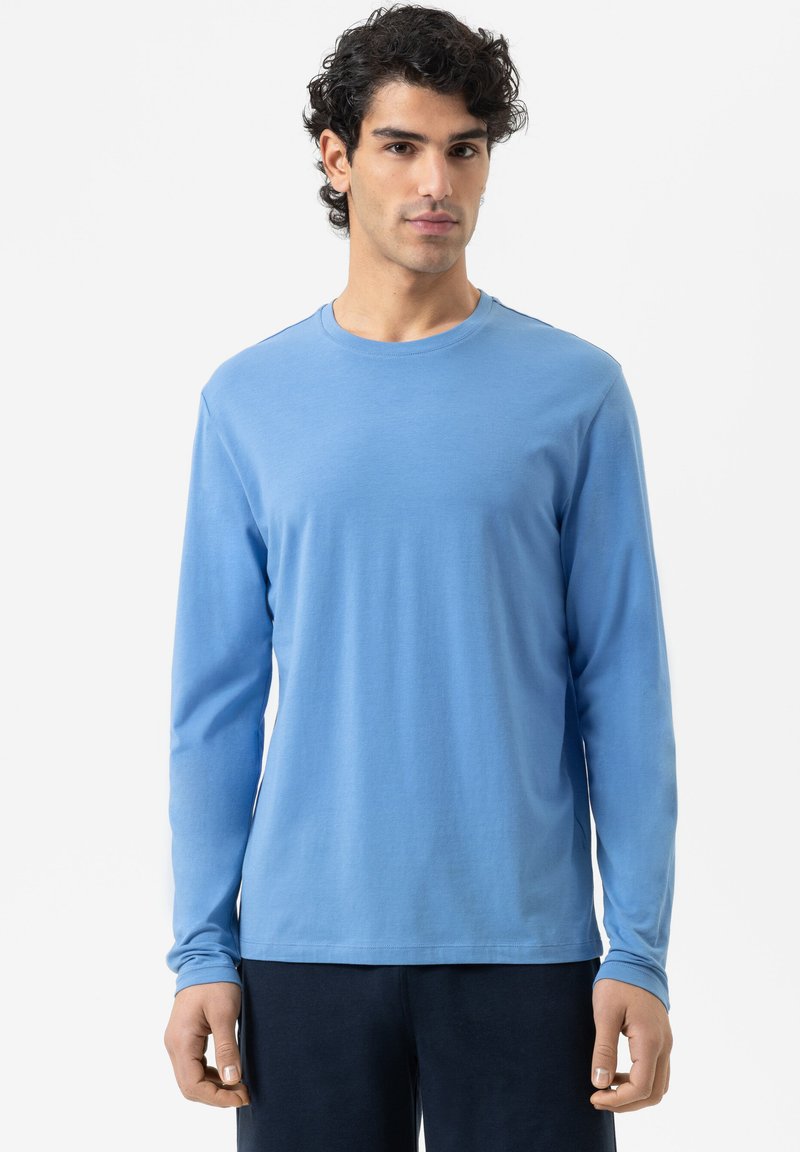 Lange mouwen blauwe shirt gemaakt van zachte stof, met een ronde halslijn en aangesloten mouwen, gecombineerd met donkere broeken.