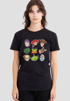 Young woman wearing black Toy Story t-shirt featuring character faces including Woody, Buzz Lightyear, Jessie, Rex, and alien on gray background.