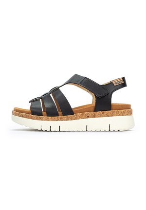 Sandalias de cuero negro con suela de corcho, correas ajustables y suela de goma blanca. Presenta correas anchas y un diseño en capas.