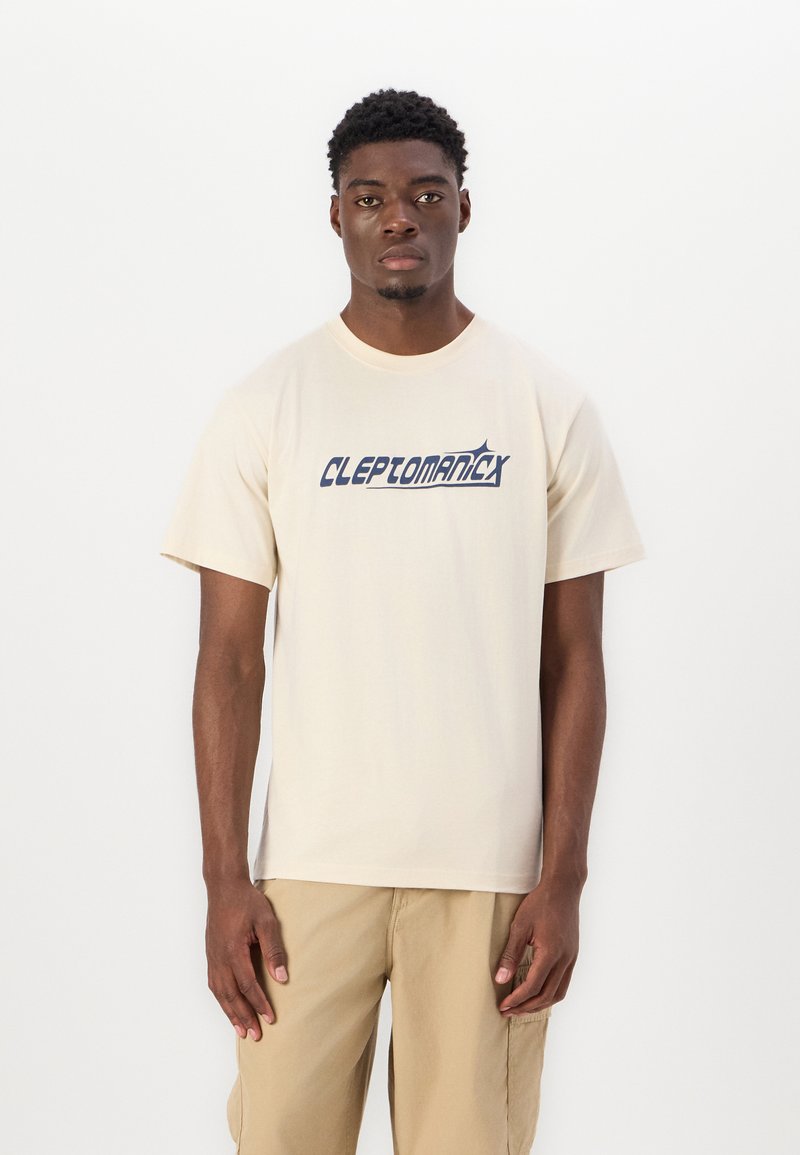 Beige cotton t-shirt with short sleeves, featuring a blue graphic logo "CLEPTOMANIX" across the chest. Simple design, relaxed fit.