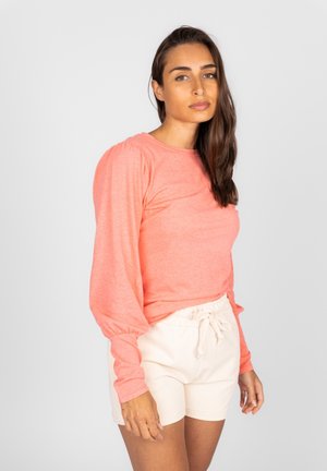 Koraal lange mouwen shirt met pofmouwen, gecombineerd met crèmekleurige shorts. Het bovenstuk heeft een ronde halslijn en een zachte textuur.
