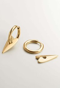 Pendientes de metal color dorado con un cierre en forma de corazón y un acento puntiagudo. Superficie suave con un acabado brillante. Diseño minimalista.