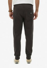 Donkergrijze joggingbroek van zachte stof, met een elastische tailleband, geribbelde boorden en een achterzak met een klein logo. 