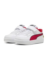 Zapatillas blancas con una correa de velcro, que presentan una franja lateral roja y un logo negro. Parte superior de sintético liso y suela de goma texturizada.