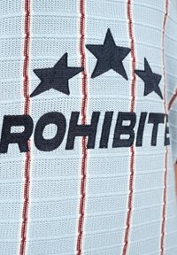 Tissu tricoté bleu clair avec des rayures verticales rouges, comportant trois étoiles noires au-dessus du mot partiel "PROHIBITE" en lettres noires en gras.