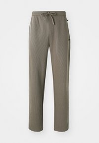 Slim-fit, hellbraune Jogginghosen aus strukturiertem Stoff. Mit einem verstellbaren Kordelzugbund und einem kleinen Logo an der Seite.