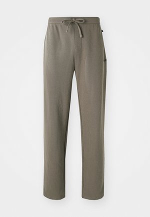 Pantalons de jogging slim-fit, couleur marron clair, fabriqués à partir d'un tissu texturé. Dotés d'une taille avec cordon de serrage ajustable et d'un petit logo sur le côté.