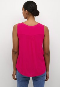 Blusa sin mangas rosa conescote redondo, sutil detalle de pliegue en la parte posterior y un dobladillo curvado. Fabricada en tejido ligero y texturizado.