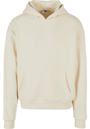 Kremeni dukserica s kapuljačom, prednjim džepom, rebrastim manžetama i rubom. Napravljena od mekog materijala s glatkom teksturom. Opuštenog, ležernog kroja.