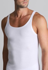 Top in cotone bianco senza maniche con scollatura all'americana, vestibilità slim e spalline larghe. La texture liscia mette in risalto un design semplice e classico.