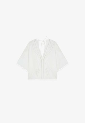 Blouse blanche avec un profond décolleté en V, manches kimono courtes et broderies délicates. Finition avec un ourlet festonné et une fermeture à nouer à l'arrière.