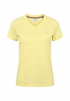 Camiseta amarilla de mujer con cuello en V y mangas cortas, con pequeño logo bordado en el lado izquierdo del pecho y detalle de rayas en el interior del cuello.