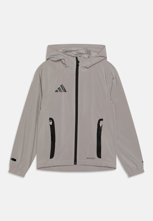 Light grey jacket with a hood, zip front, black zippered pockets, and black logo. Made from smooth, lightweight material with elastic cuffs.