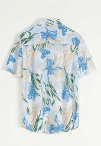 Chemise à manches courtes en tissu bleu clair présentant un motif floral avec des fleurs bleues et beiges, des feuilles vertes, et une coupe décontractée.