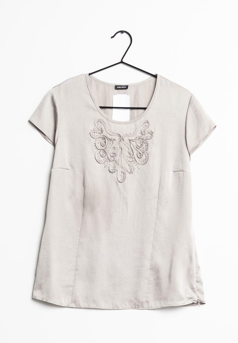 Top corto e grigio chiaro a maniche corte realizzato in tessuto morbido, con ricami decorativi a motivo floreale sul collo e uno spacco laterale.