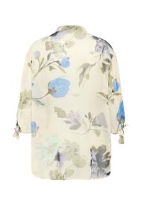Blusa floreale con una base color crema chiaro, decorata con stampe botaniche blu e verdi. Maniche lunghe legate ai polsini; tessuto leggero e semi-trasparente.