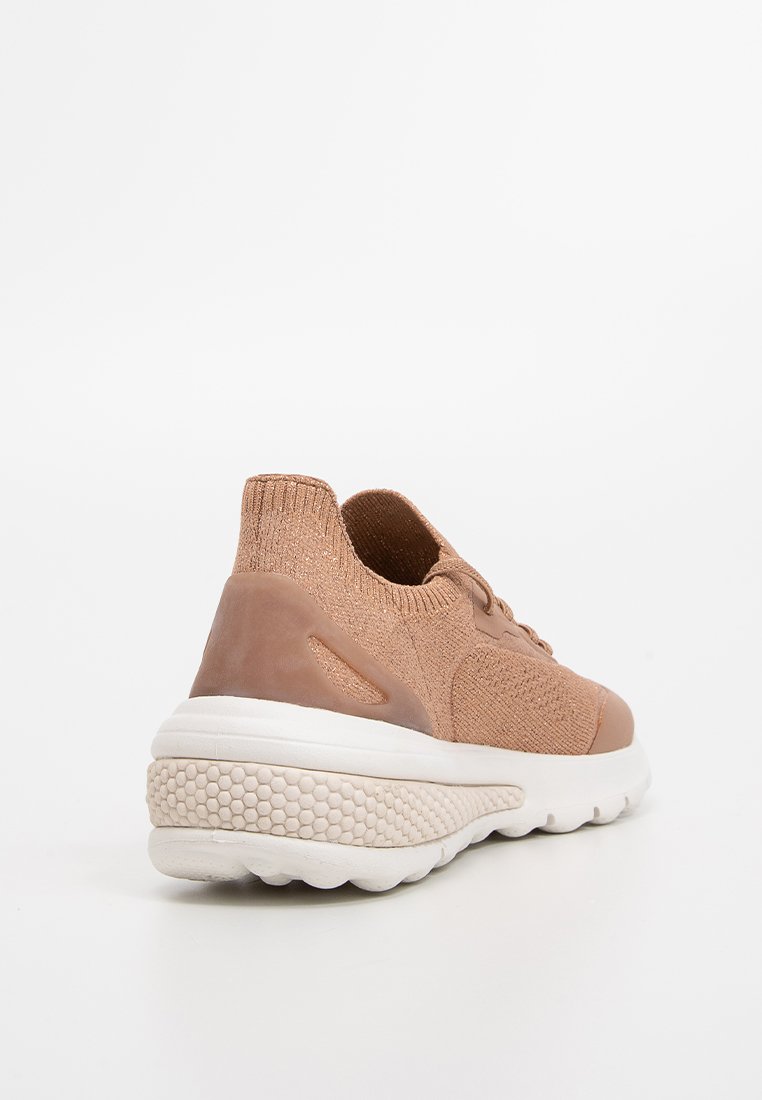 Jasnobrązowy but sportowy z teksturowaną cholewką z dzianiny i gładkim brązowym zapiętkiem. Posiada grubą białą podeszwę z heksagonalnym wzorem.