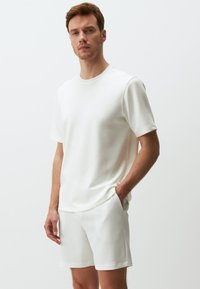 Set di t-shirt a maniche corte e pantaloni corti bianchi, caratterizzato da una vestibilità comoda, una texture liscia e un design minimalista senza motivi o accenti visibili.