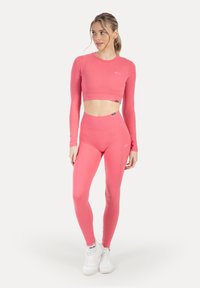 Pinkes Sportoutfit bestehend aus einem kurzen Langarm-Top und hochtaillierten Leggings, gefertigt aus glattem, elastischem Stoff mit dezentem Markenlogo.