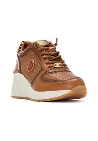 Zapatilla marrón con cuero texturizado y acentos lisos. Cuenta con una gruesa suela blanca y un detalle decorativo del logo en el costado.