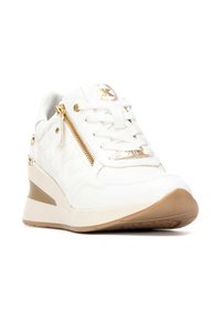 Zapatillas blancas con textura acolchada, herrajes dorados, detalle de cremallera y suela elevada. Presentan un frente con cordones y suela color tostado.