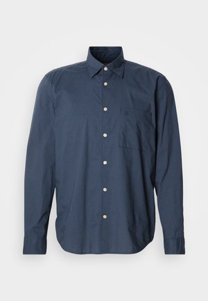 Tummansininen napillinen paita pitkillä hihoilla, pieni ruutukuosi, yksi rintatasku ja valkoiset napit yksinkertaisella taustalla.