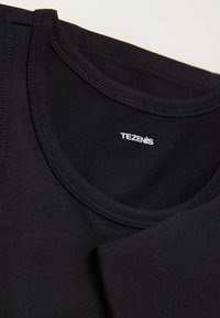 Czarna bawełniana koszulka z okrągłym dekoltem, z przeszytymi brzegami oraz małą białą metką "TEZENIS" w pobliżu kołnierza.