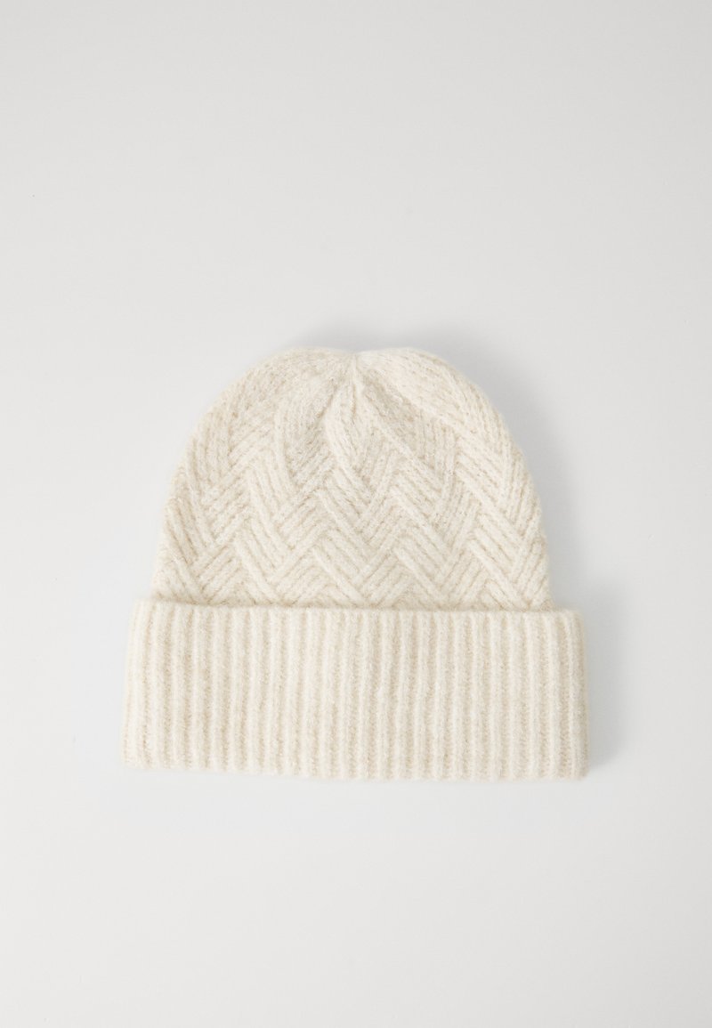 Gorro de punto color crema con un borde ribeteado doblado y un patrón de zigzag en el cuerpo principal.