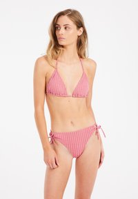 Roze prugasti bikini s trokutastim gornjim dijelom i podesivim donjim dijelom sa vezanjem sa strane. Tkanina ima glatku teksturu, s suptilnim sjajem i pažljivo oblikovanim linijama.