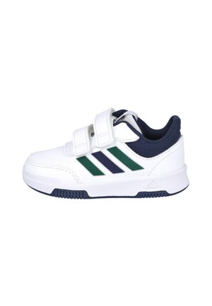 Zapatilla blanca con dos cintas de Velcro, acentos en azul marino y tres rayas en ángulo en verde oscuro y azul marino. Suela de goma con texturizado.