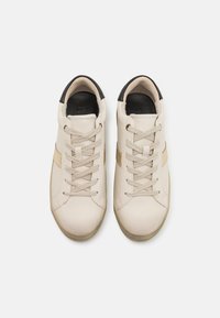 Beez sneakerid tekstuuriga nahkpealsega, musta kanna ja kuldse aktsenttriibuga. Omab lamedaid nööre ja ümarat otsa disaini.