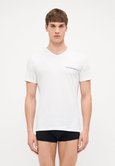 White short-sleeve V-neck t-shirt with a left chest logo, showcasing a smooth texture and modern fit. Worn with dark boxer briefs.
