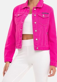 Pink denimjakke med sølvfarvet hardware, to brystlommer og cropped design. Har kontrastsyninger og knaplukning foran.