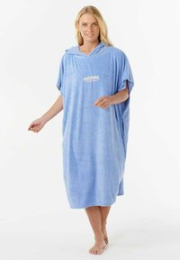 Poncho con capucha de rizo en azul claro, con un logo en la parte delantera. Corte holgado con mangas cortas y bolsillos a los lados. Modelo descalzo.