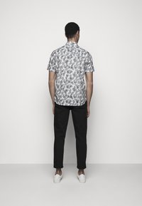 Lyhythihainen paita yksivärisellä lehtikuvioinnilla, harmaa ja valkoinen. Yhdistetty mustiin housuihin ja valkoisiin slip-on-kenkiin.